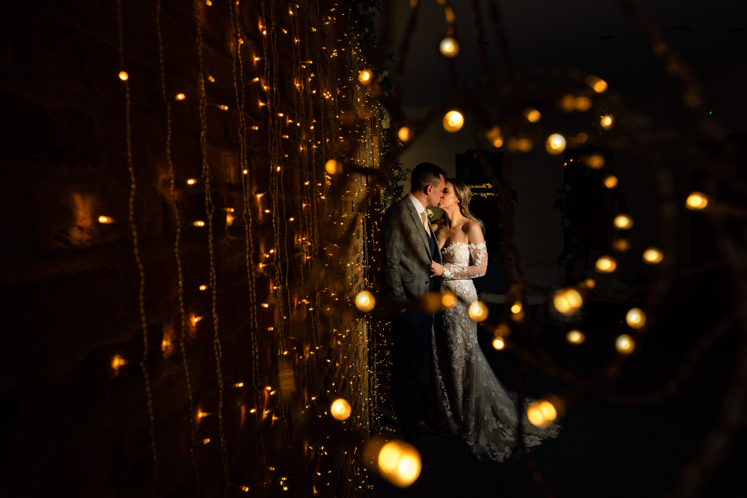 North Yorkshire Wedding Photographer bride and groom kissing against a fairy lit wall